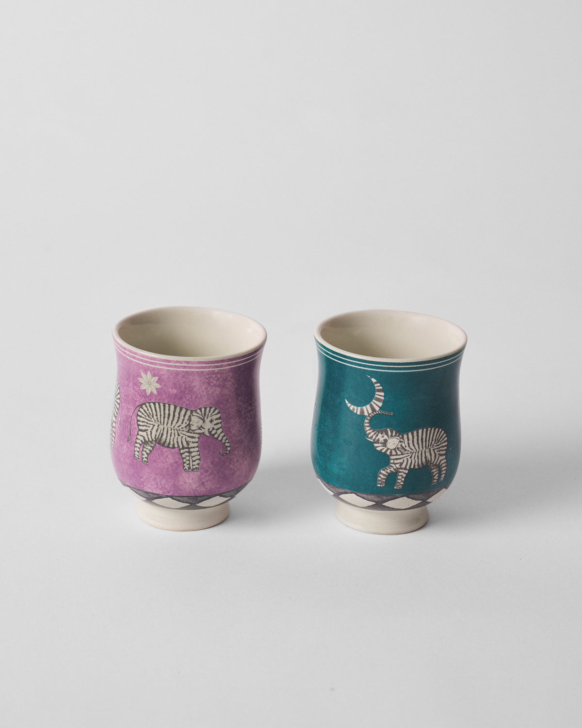 Pair of Tusk tea cups in purple and teal with striped elephants.