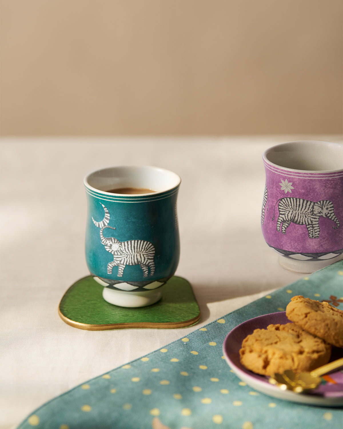 Tusk tea cups styled with tea, cookies, and a green coaster.