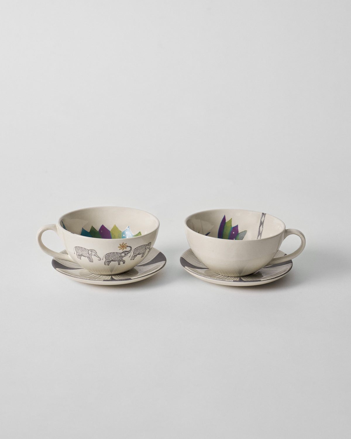 Palm Bloom coffee cups with saucers showing elephant exteriors and colorful interior rims.