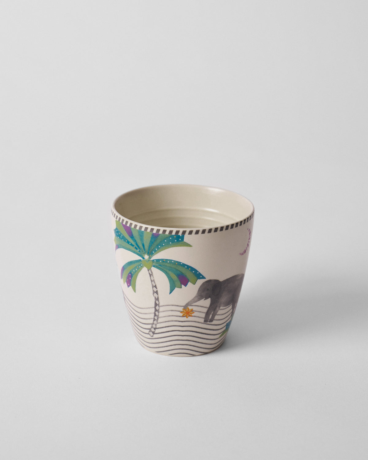 Side view of a Tusk Conical Mug with a palm tree and elephant motif.