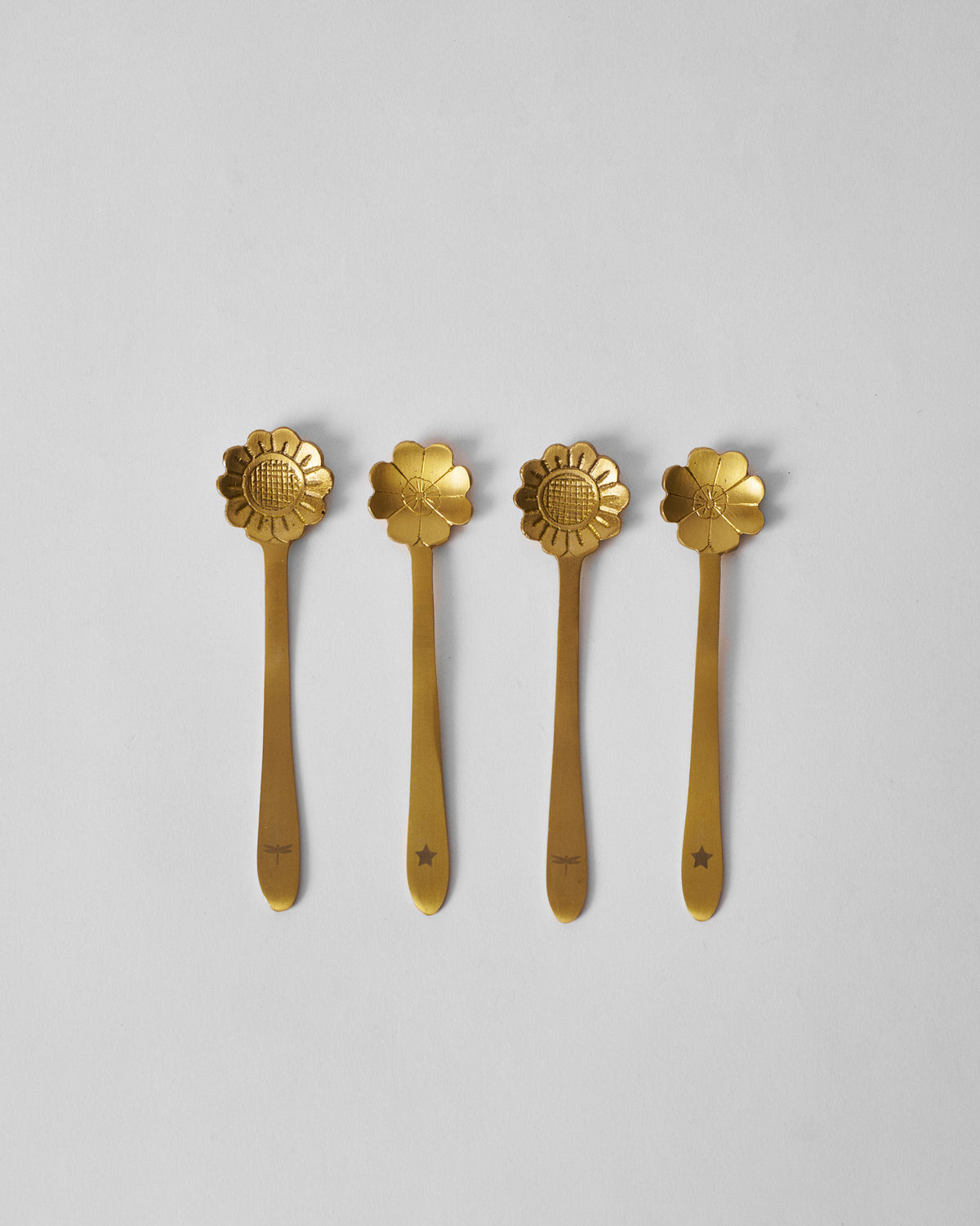 Set of four gold Phool coffee spoons with sunflower and five-petal flower heads.