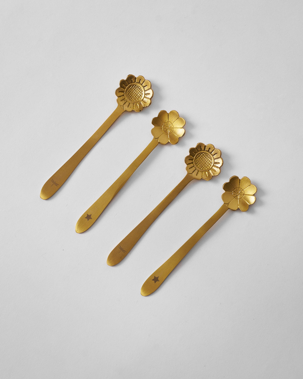 Four gold Phool coffee spoons laid diagonally with flower heads and handle stamps.
