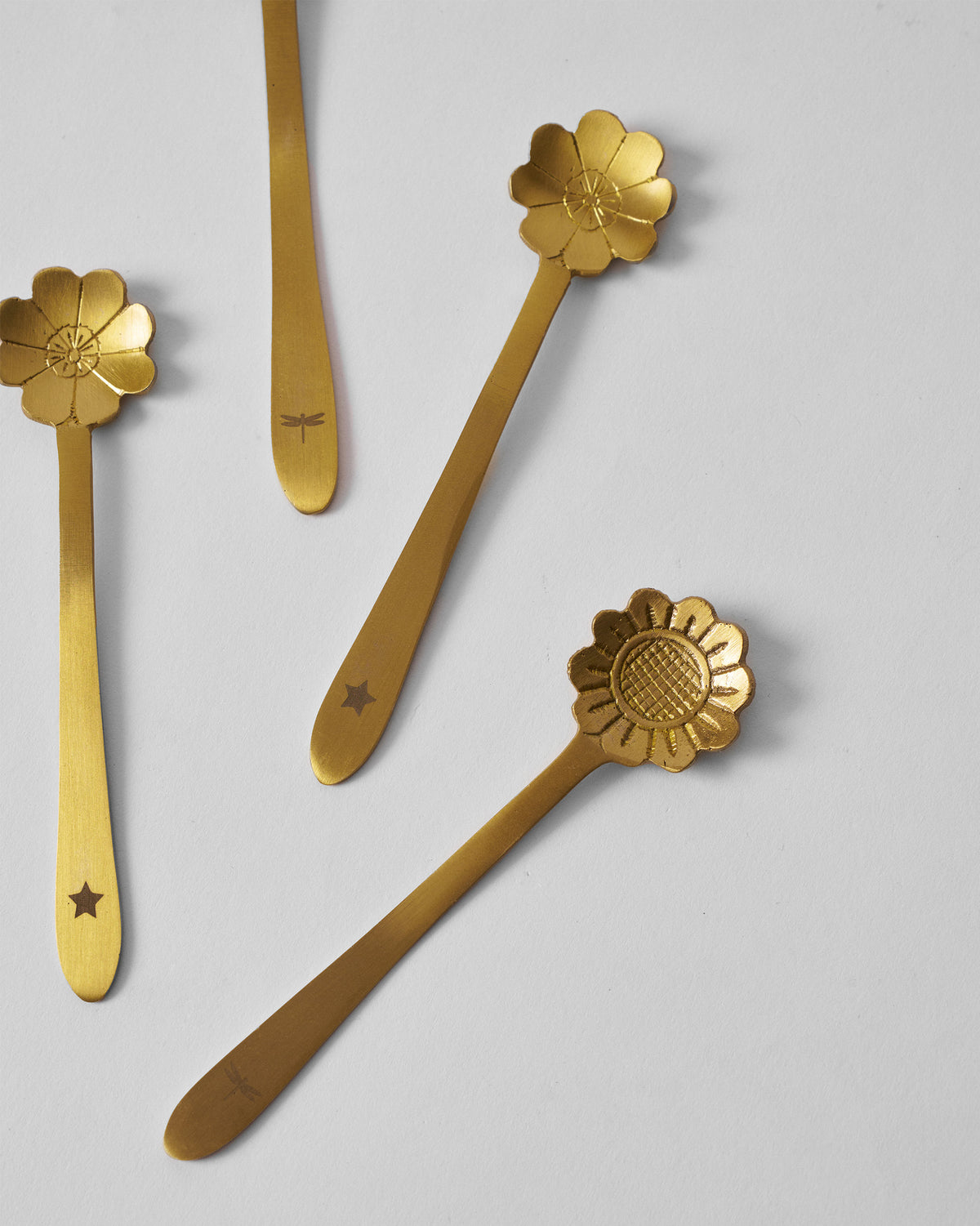 Gold Phool coffee spoons scattered to show flower heads and engraved handles.
