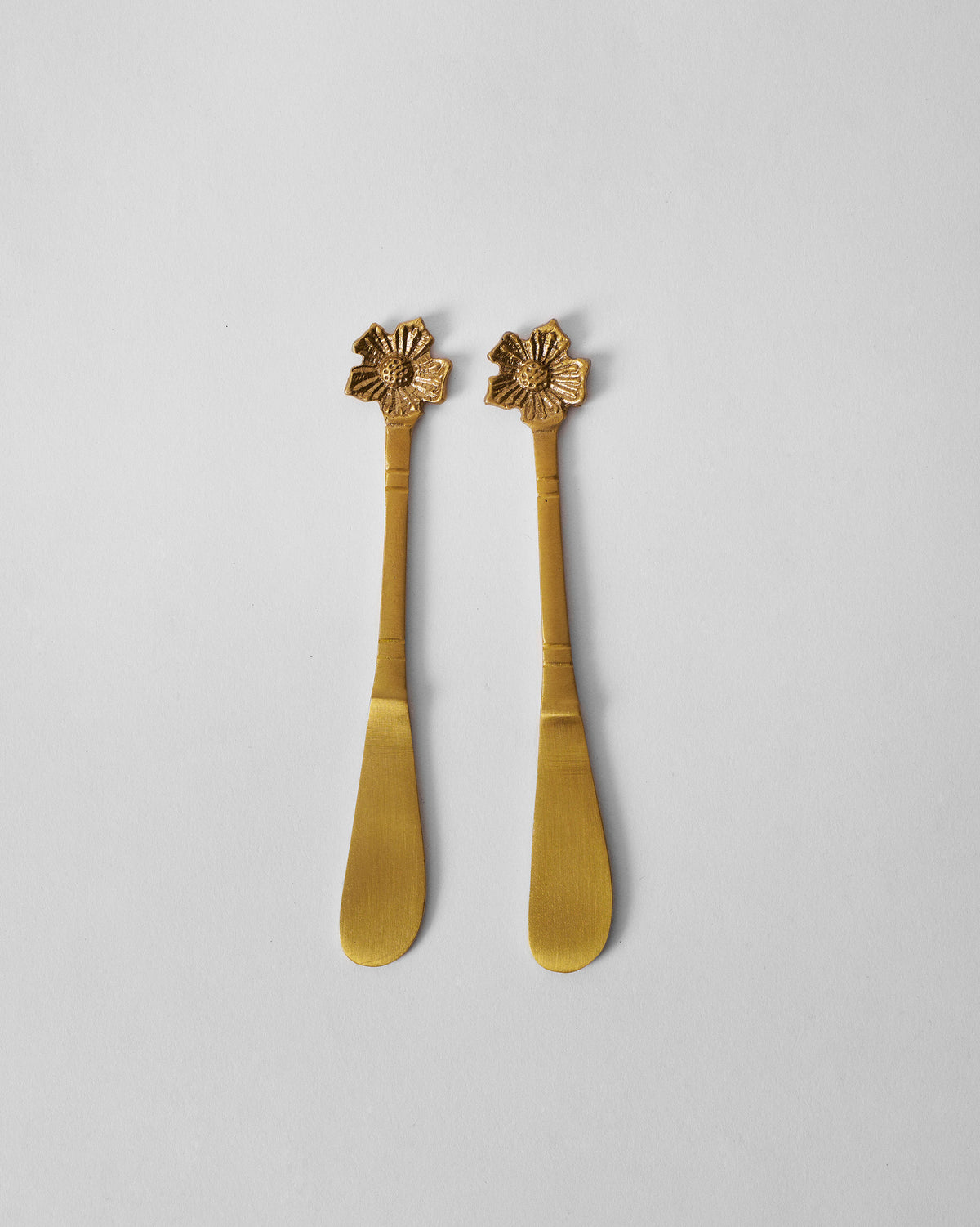Pair of gold Phool butter knives with flower finial handles.