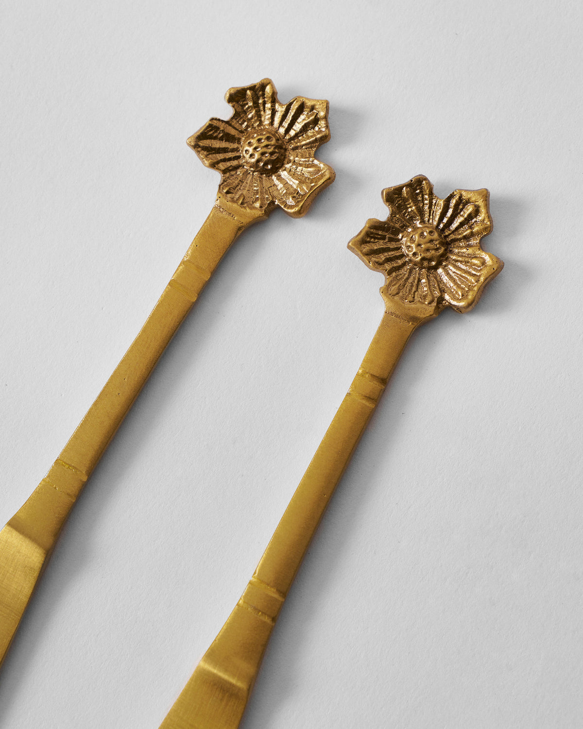 Close-up of the flower finials on gold Phool butter knives.