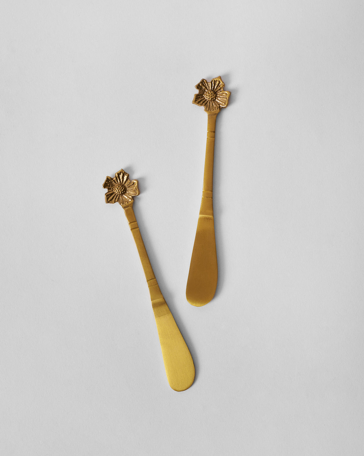 Gold Phool butter knives showing paddle blades and flower handles.