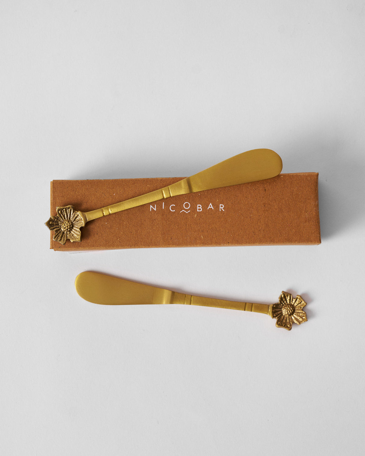 Phool butter knives arranged with their brown Nicobar gift box.