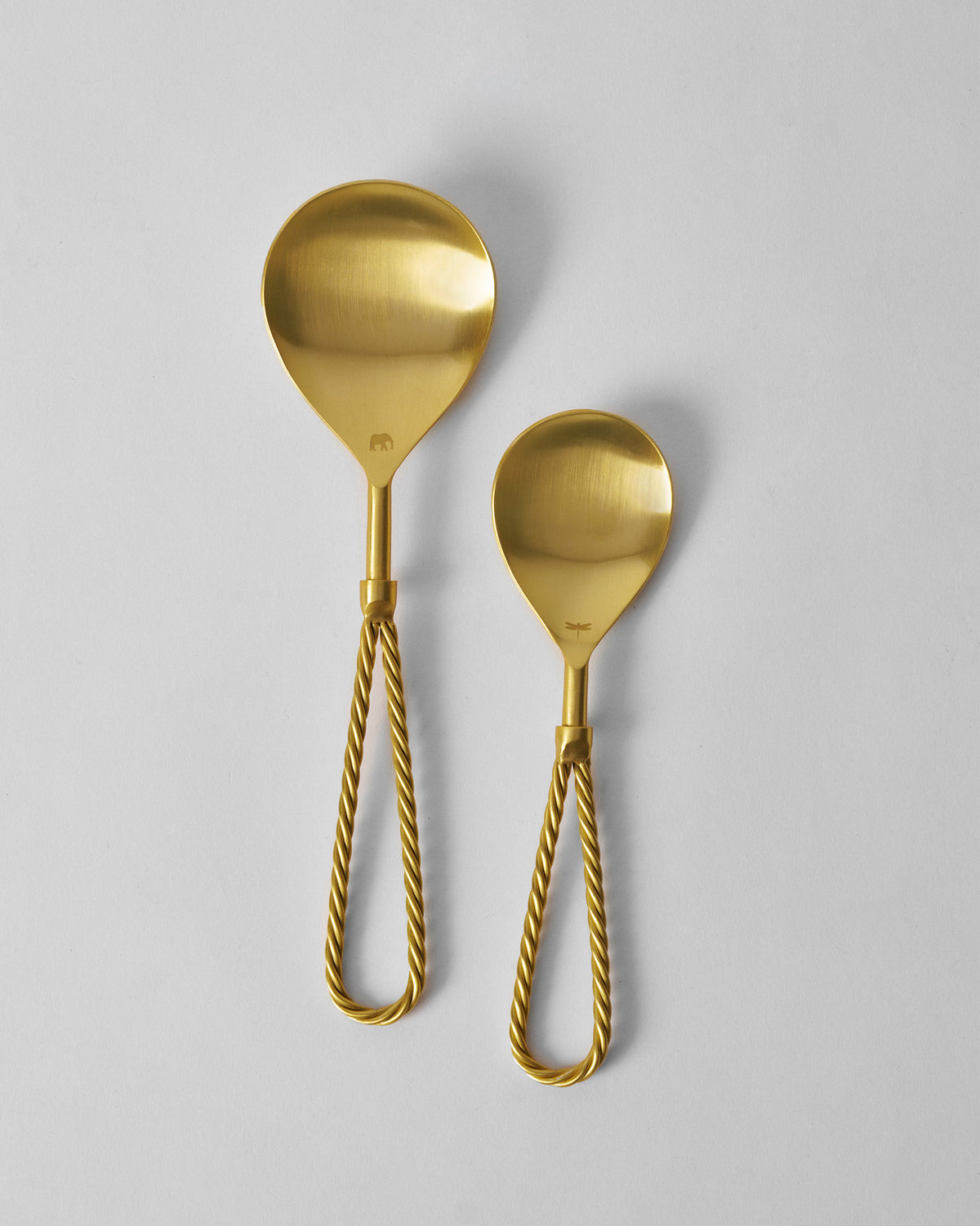 Pair of Tusk gold serving spoons with twisted loop handles.