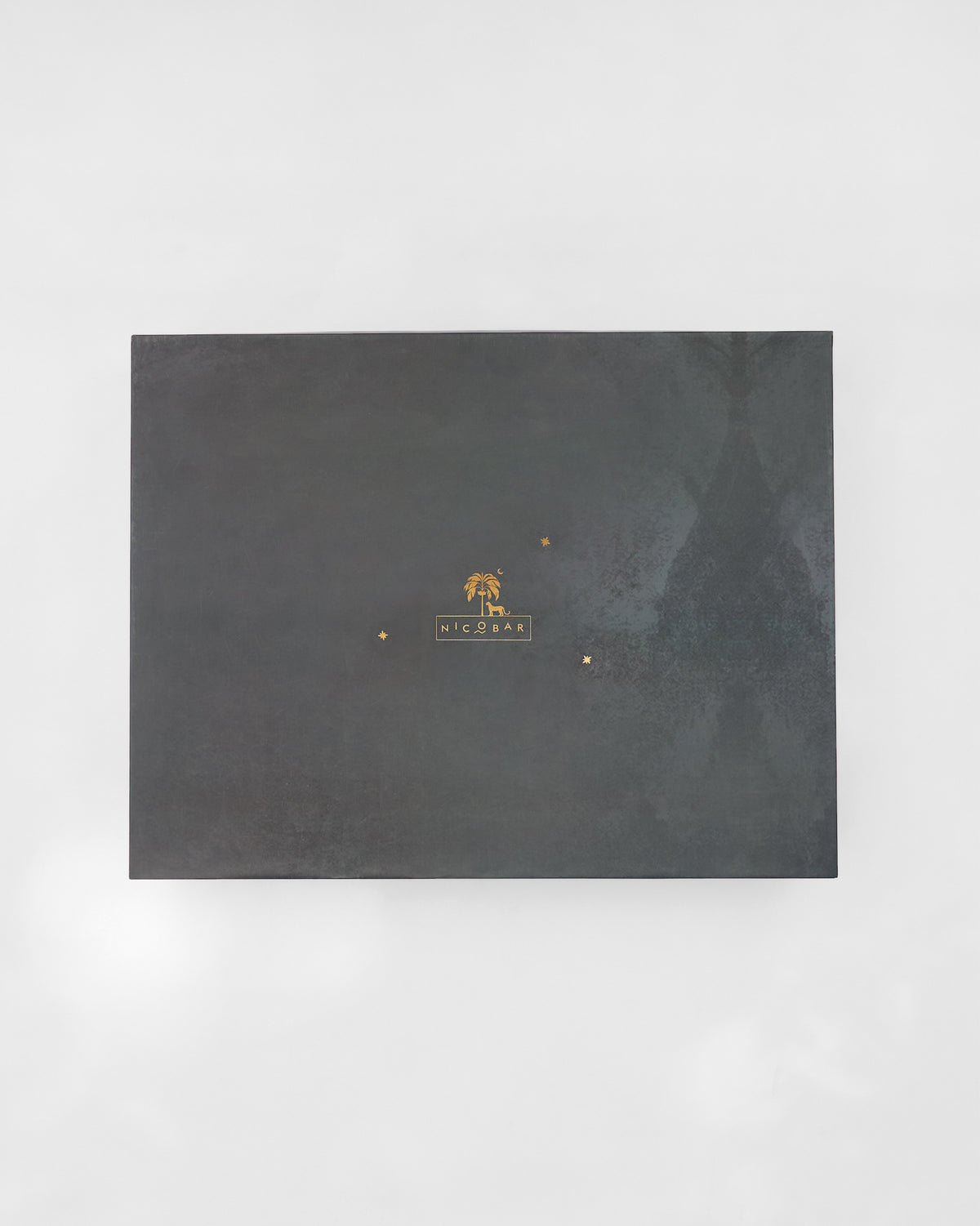 Closed charcoal Nicobar gift box for the Gilded Palm set with gold logo.