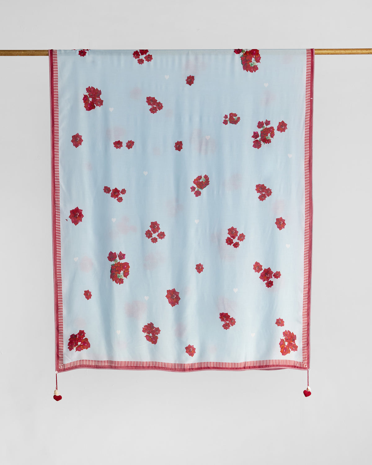 Inara Dupatta hung on a rod, showing red floral prints and a striped border.