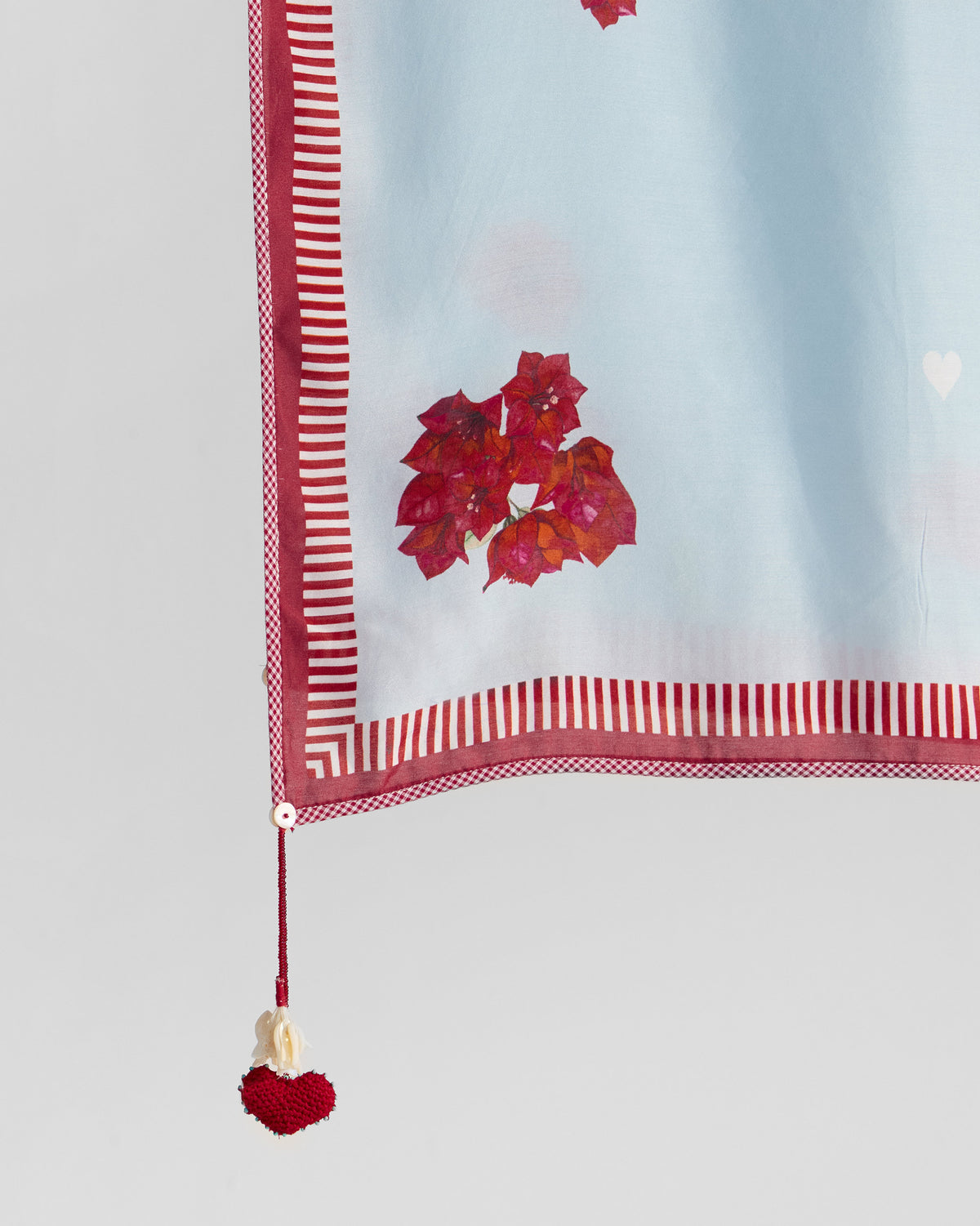 Close-up of Inara Dupatta with red floral print, striped border and heart tassel.