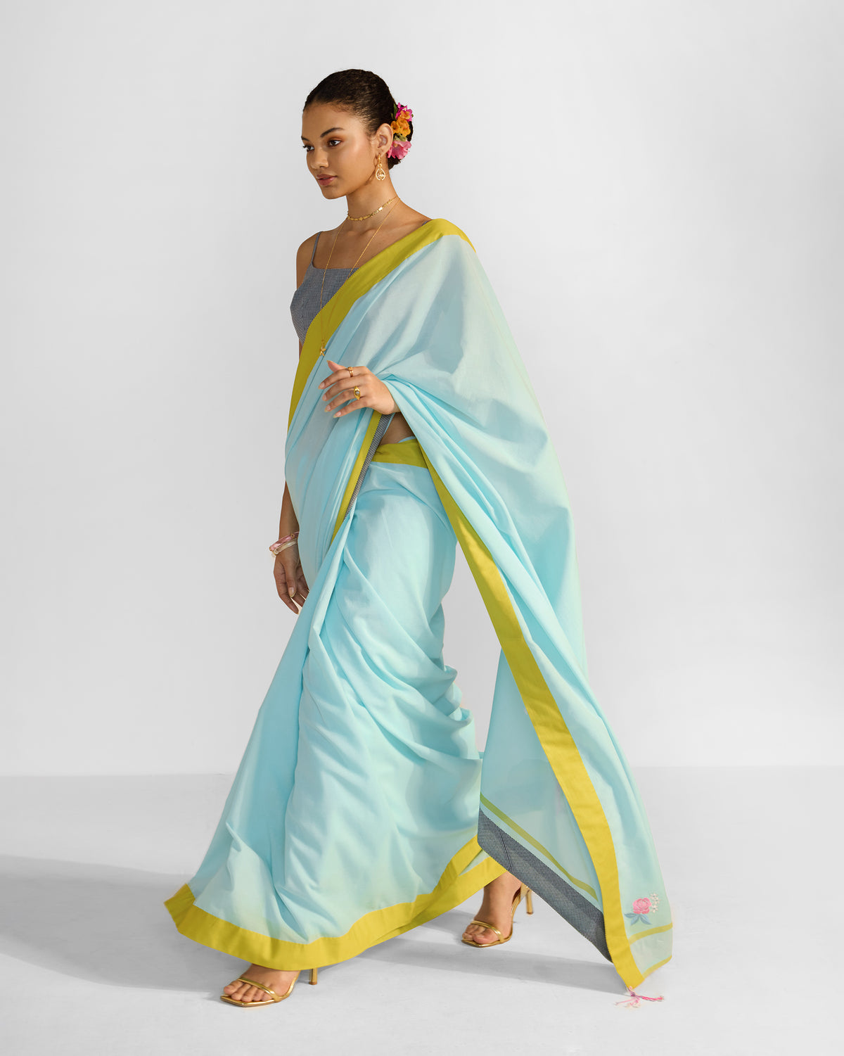 Person wearing a blue Noor sari with a chartreuse border and pink pallu tassel.