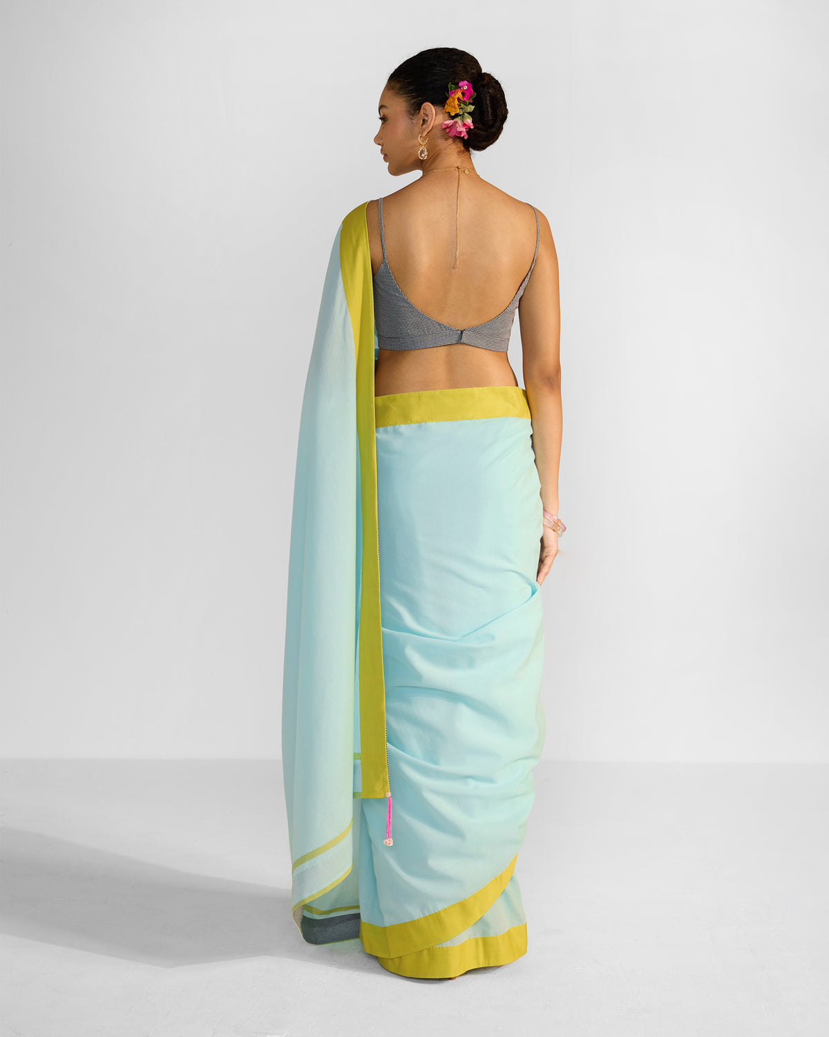 Back of a blue Noor sari with a chartreuse border draped over the shoulder.