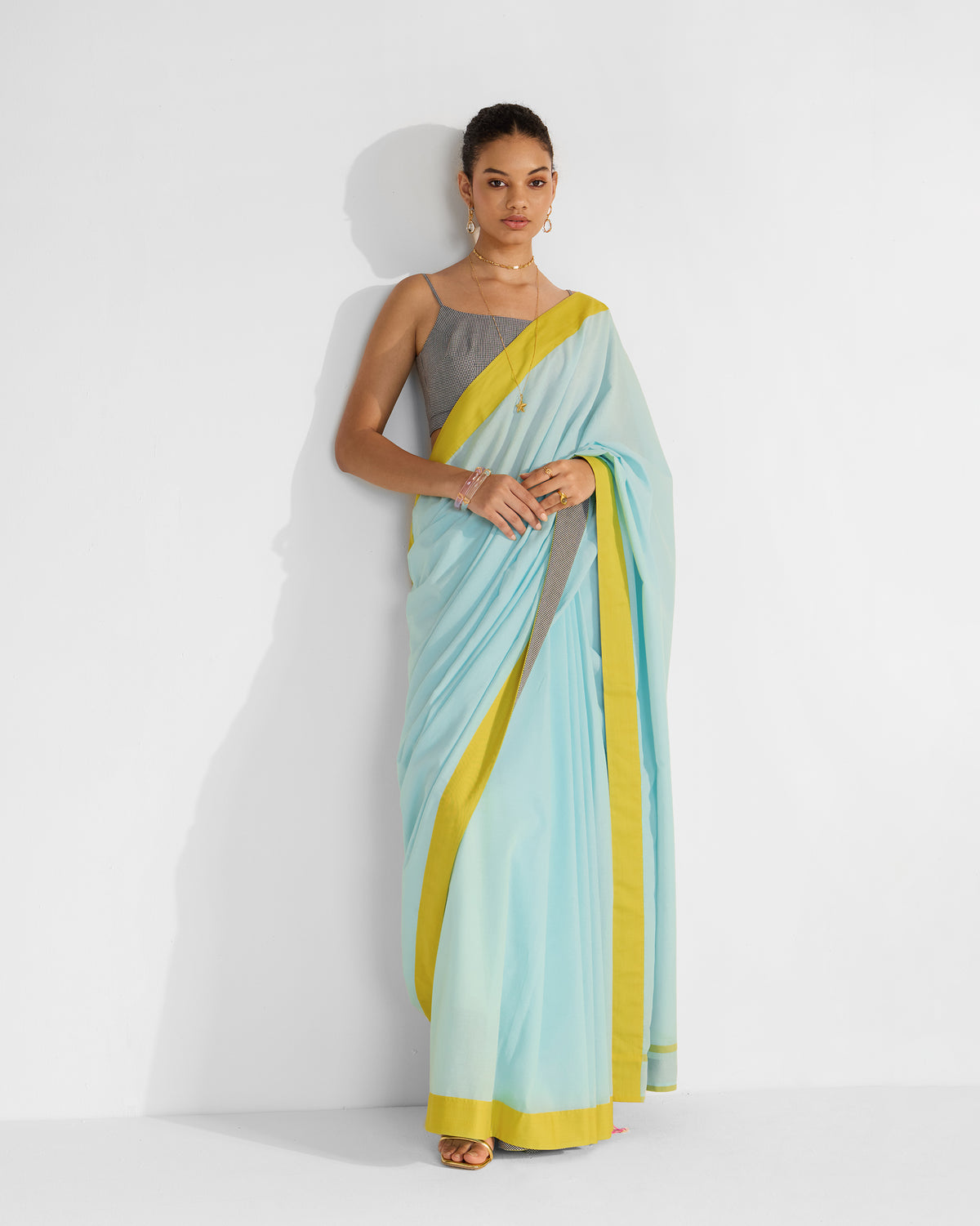 Person wearing a blue Noor sari with a wide chartreuse border.