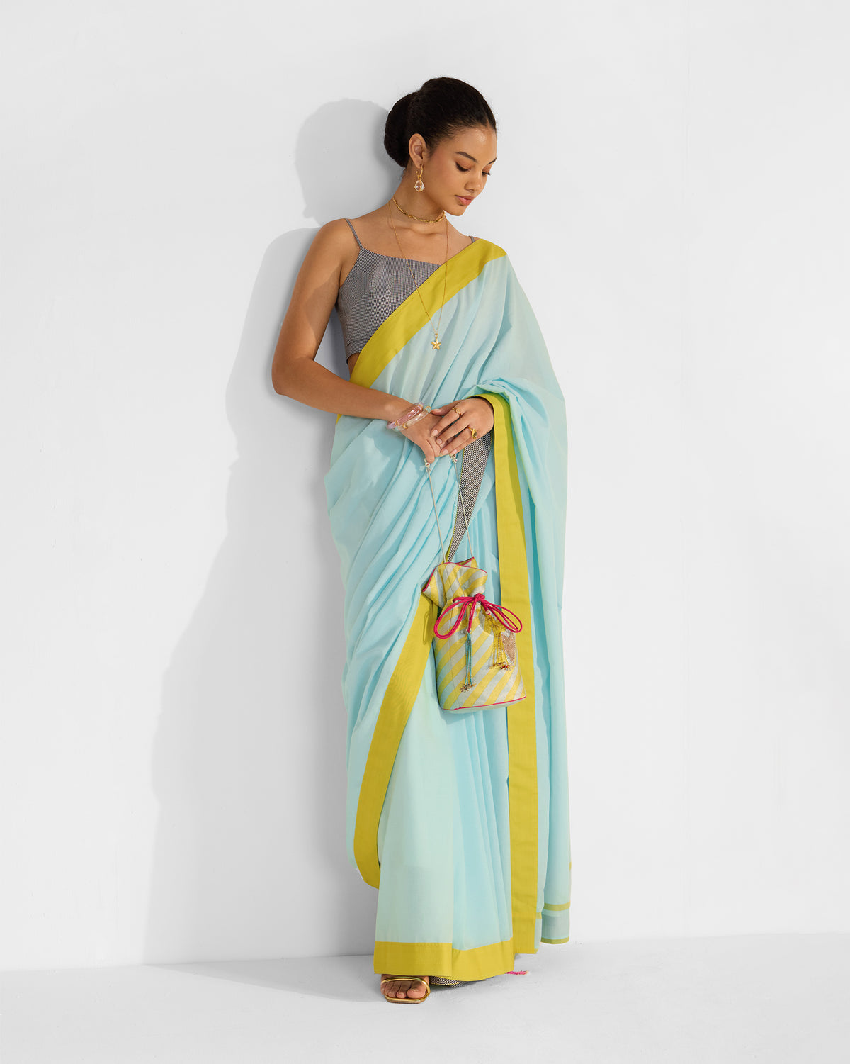 Person wearing a blue and chartreuse Noor sari with neat front pleats.