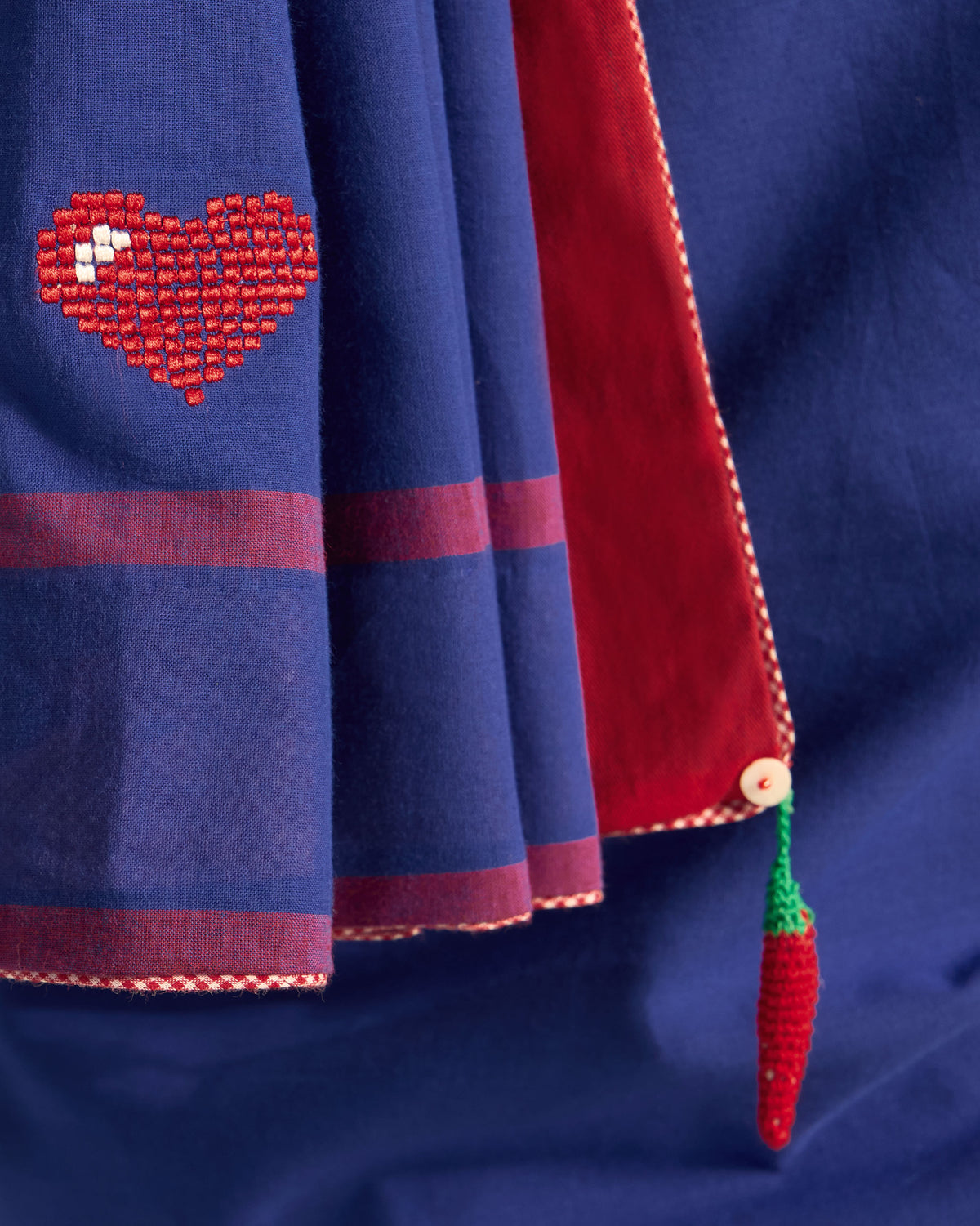 Close-up of a red heart motif and chilli tassel on a navy Noor sari.