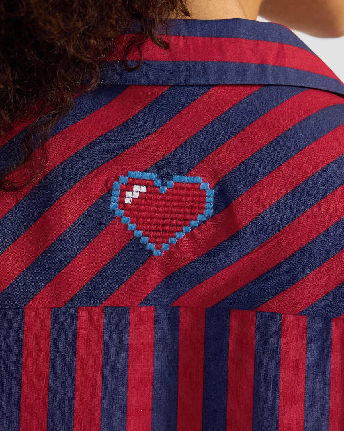 Close-up of a heart on a red and navy striped Nimar long shirt.