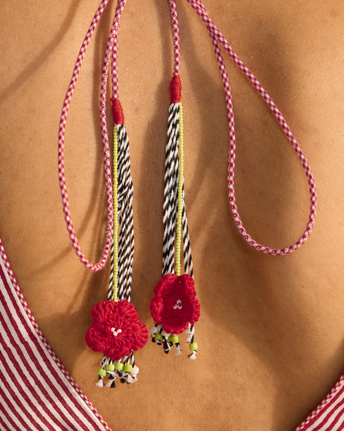 Close-up of Zahra Blouse back ties with red crochet flowers and beaded tassels.