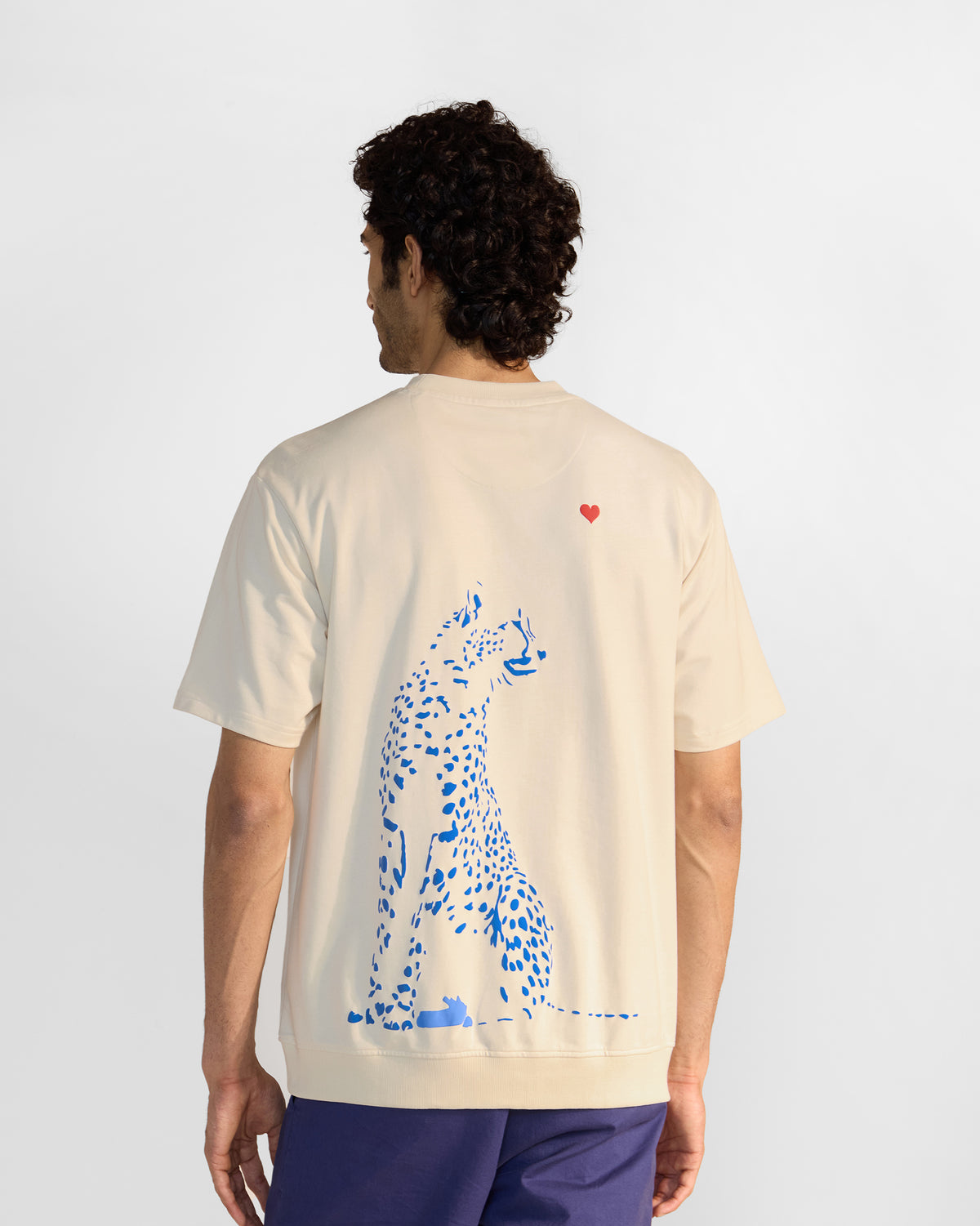 Back of an ivory leaping tiger t-shirt with a large blue leopard and red heart.
