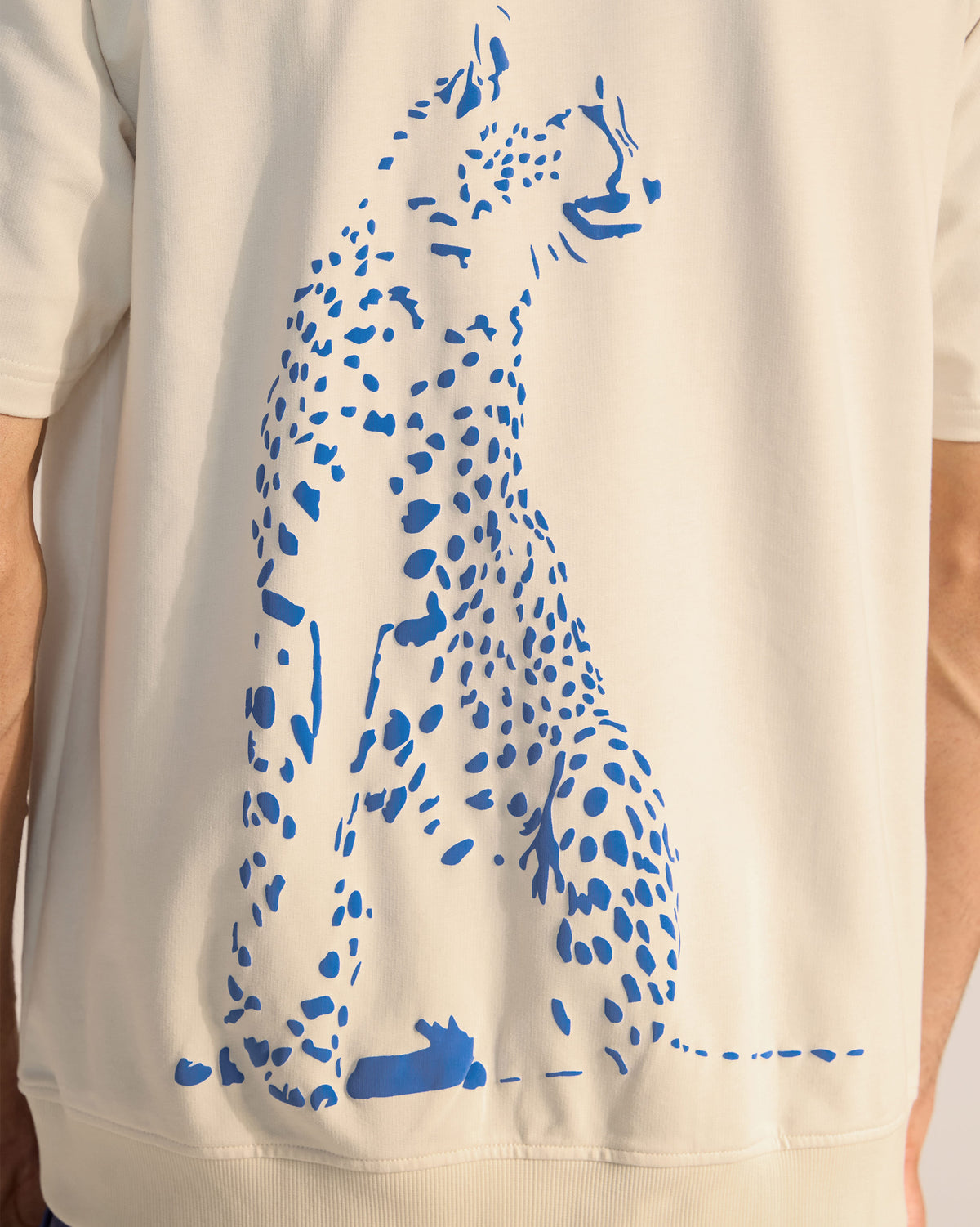 Close-up of the large blue leopard print on the back of an ivory t-shirt.
