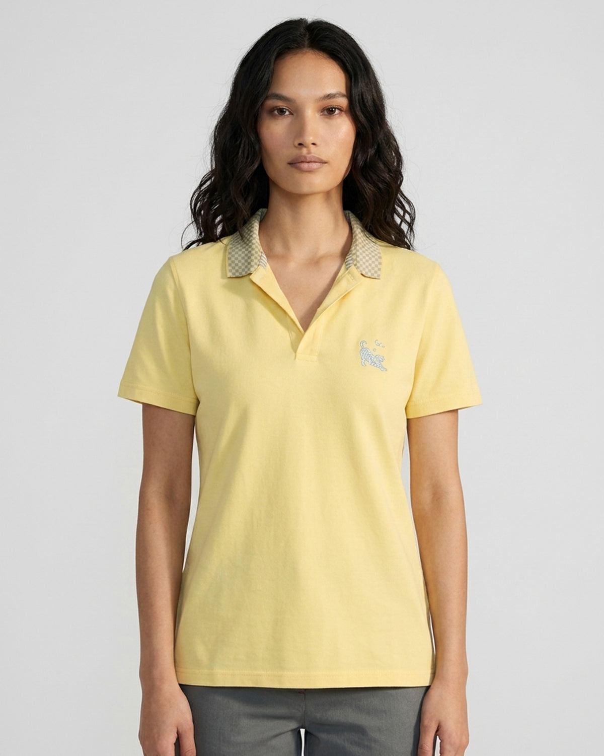 Person wearing a light yellow polo with a checkered collar and tiger embroidery.