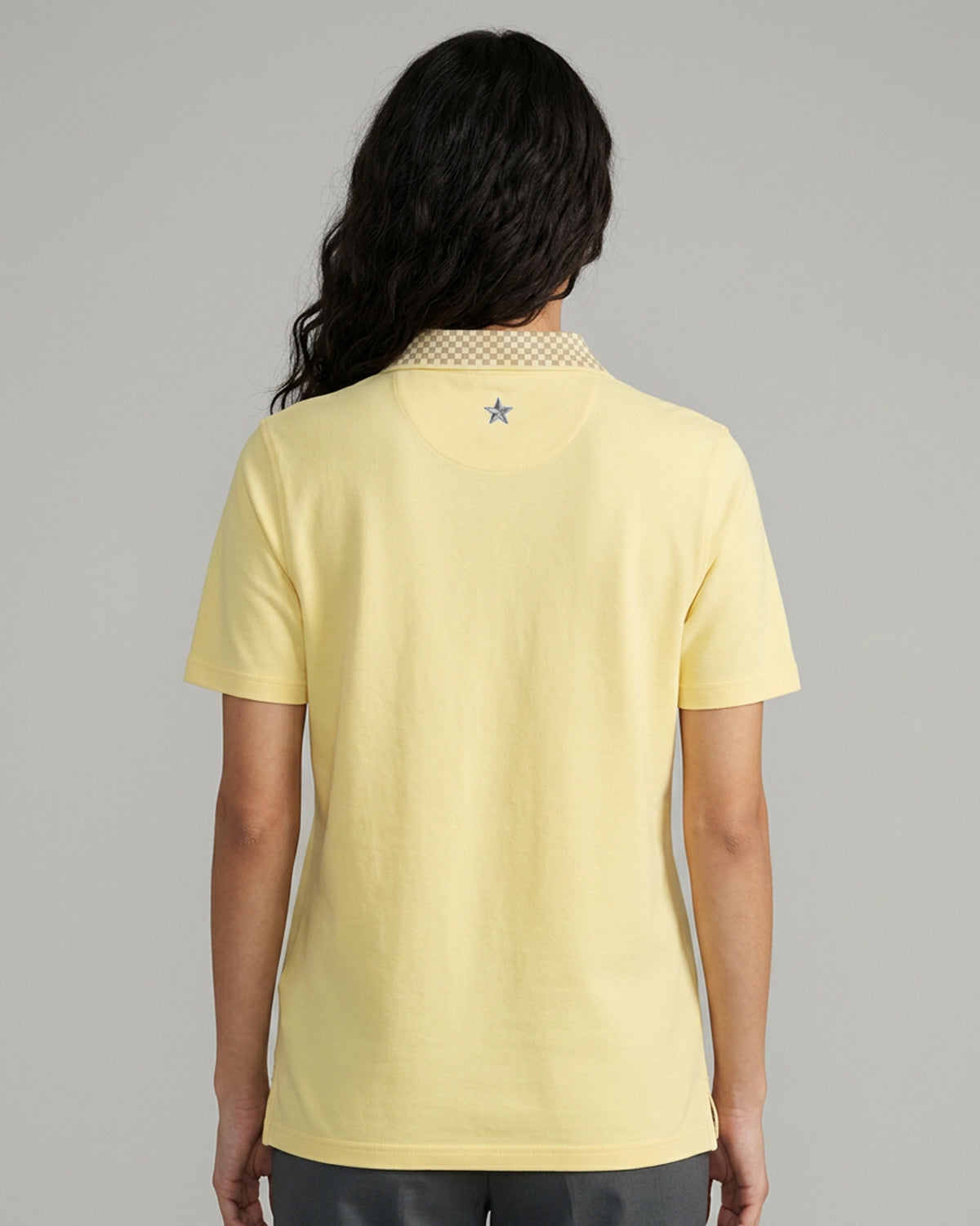 Back of a light yellow polo with a small grey star below the collar.