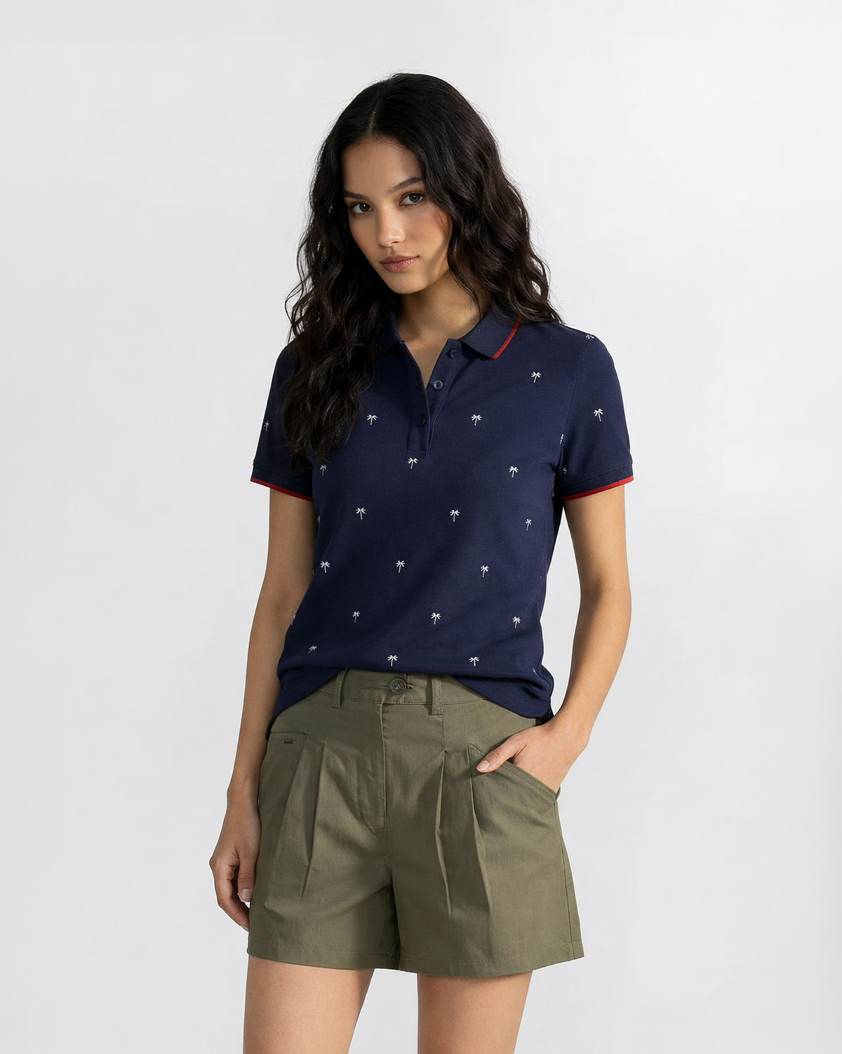Person wearing an ink blue Palma polo with a palm tree print and red tipping.