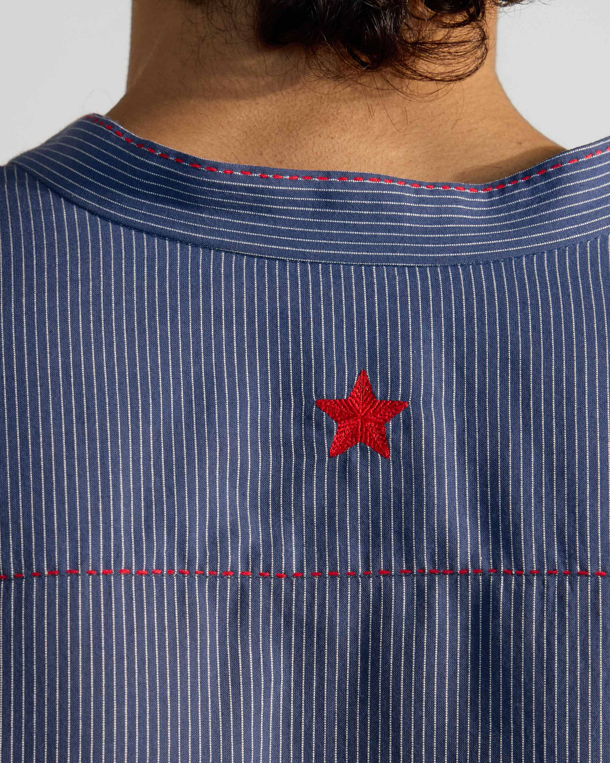 Close-up of the red embroidered star and stitching on a navy striped Nysa Kurta.