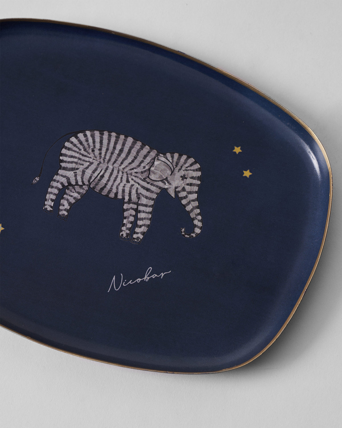 Close-up of the striped elephant and gold stars on a navy Tusk trinket tray.