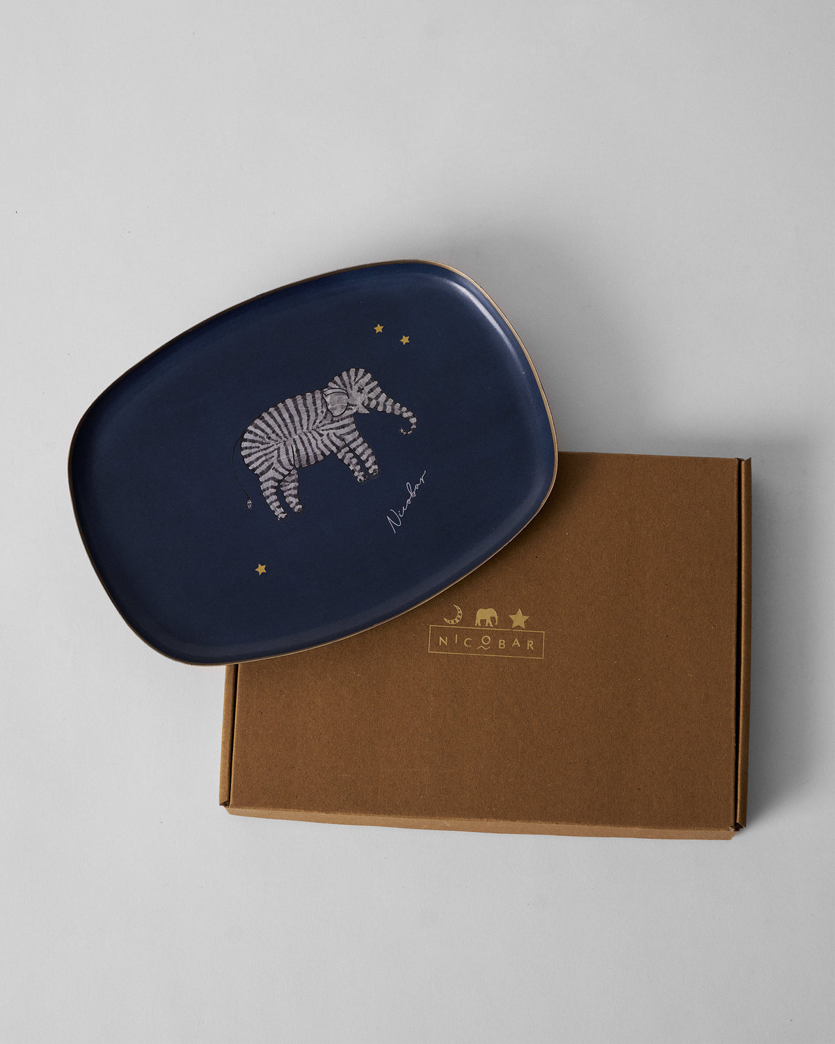 Navy Tusk trinket tray resting on its brown Nicobar gift box.