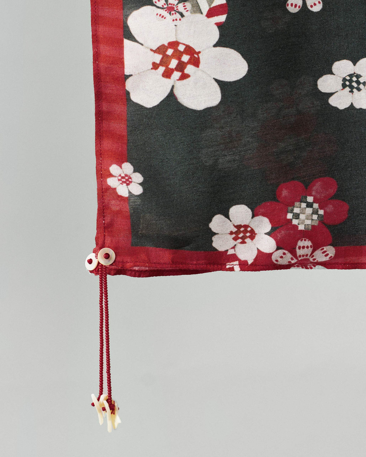 Close-up of the Fleur Scarf's red border and tasselled corner.