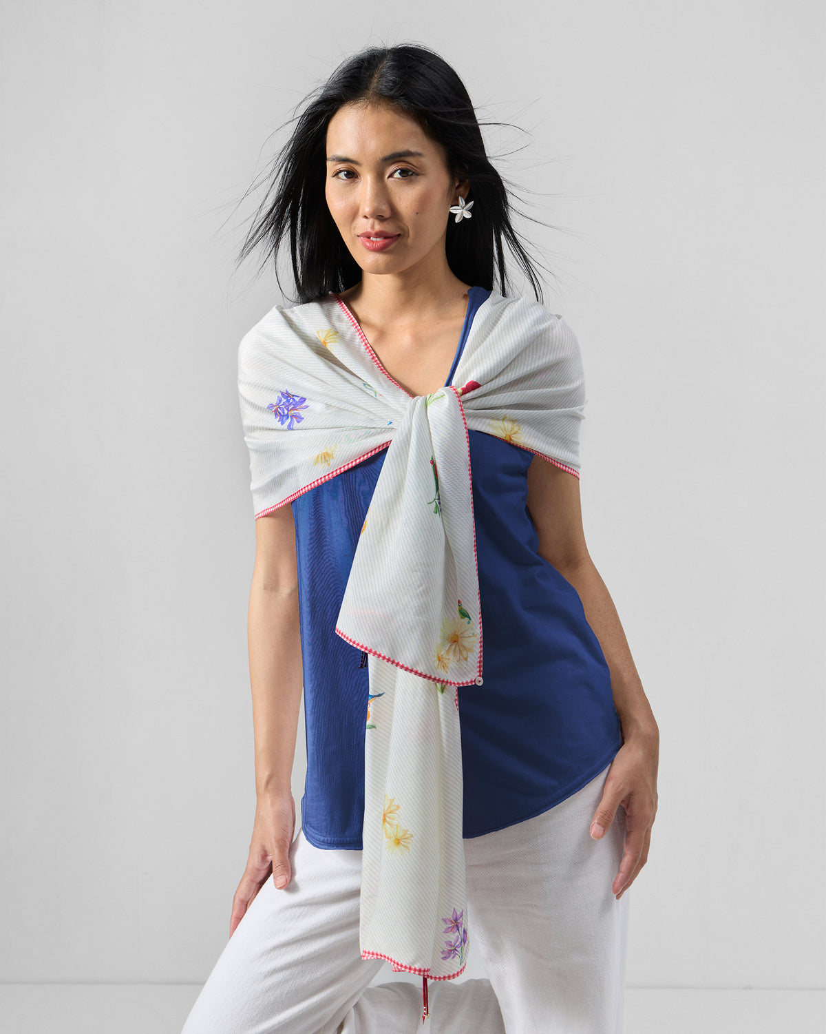 Person wearing an ivory Floral Bloom scarf with small flowers and red edging.