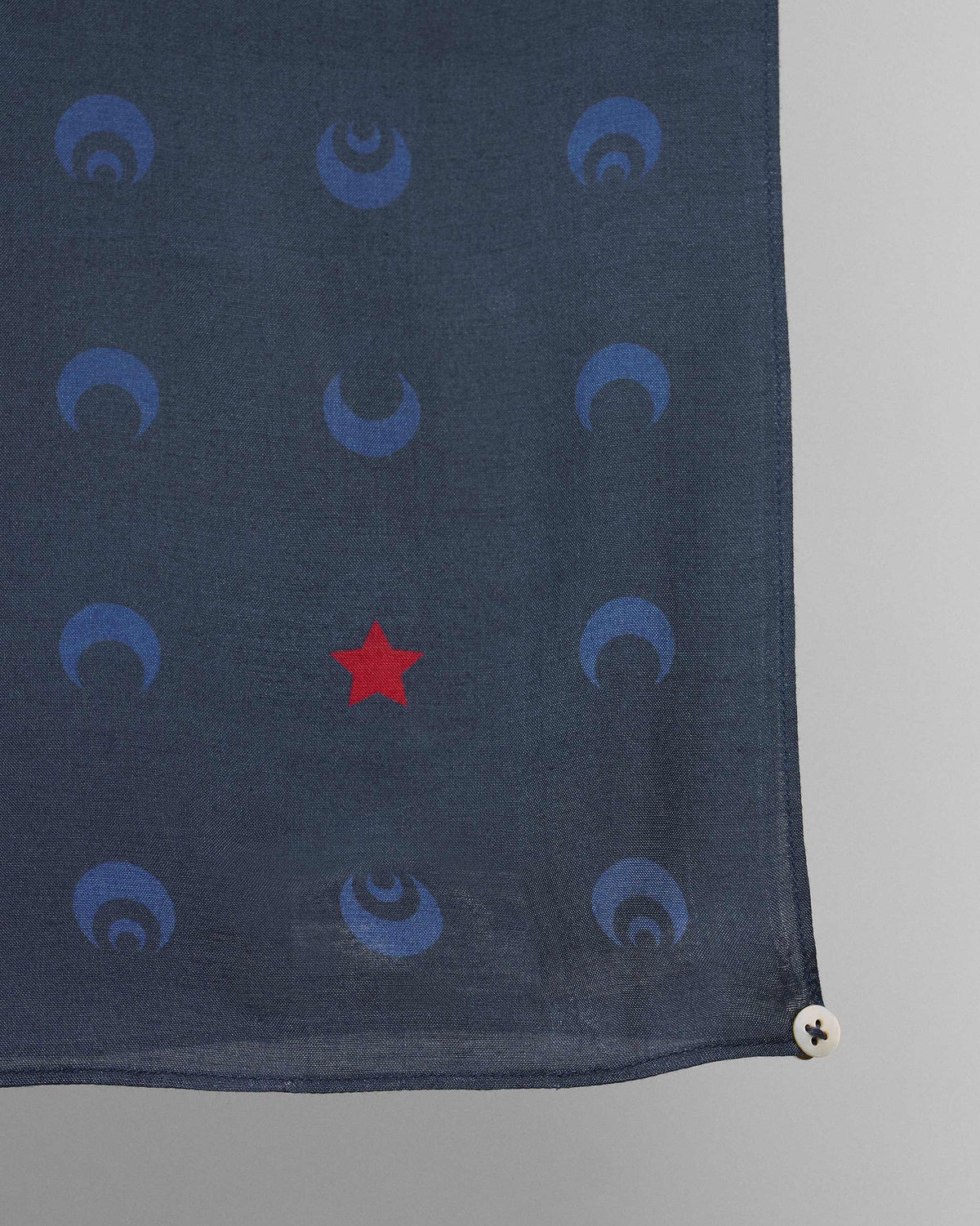 Close-up of navy Moonlit scarf corner showing crescent moons and a red star.