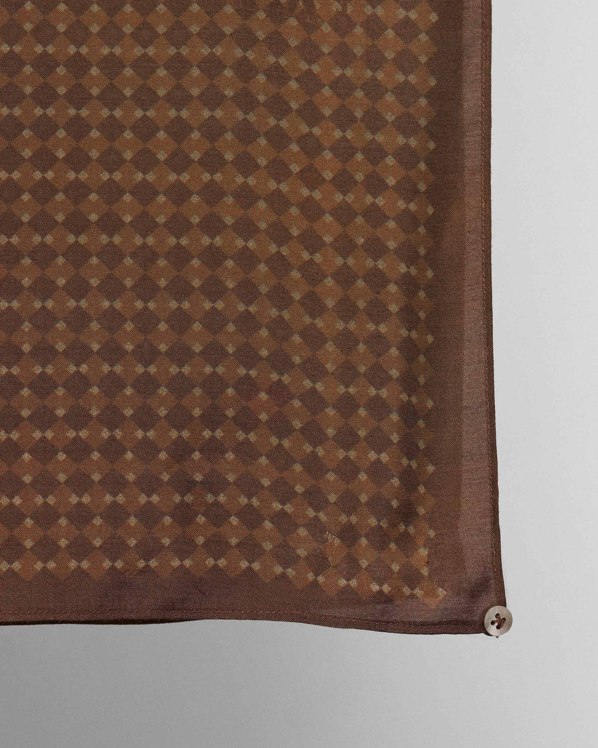 Close-up of a Heera scarf corner showing a diamond dot pattern and a shell button.
