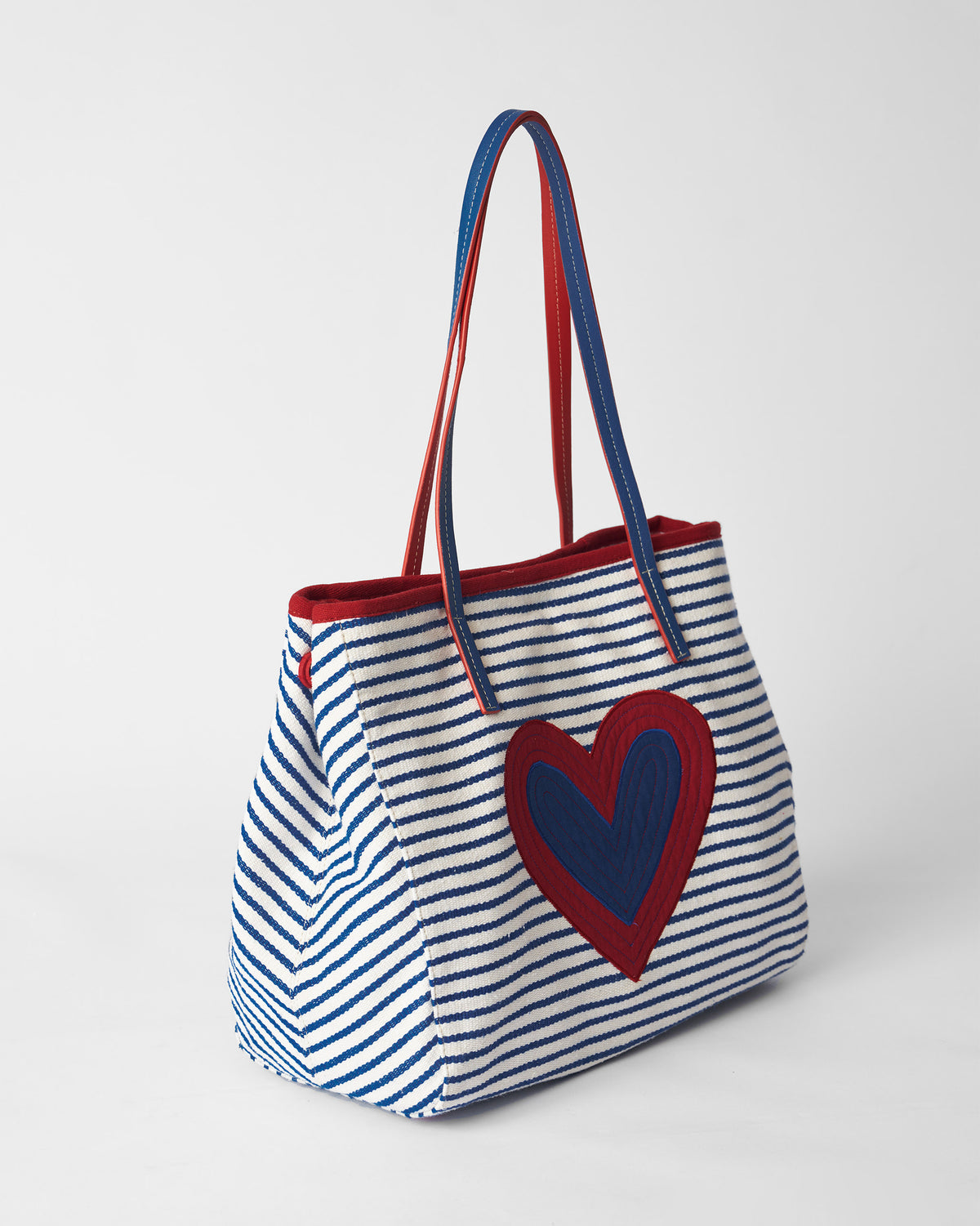 Blue and white striped Kira Bag with a red and blue heart, shown at an angle.