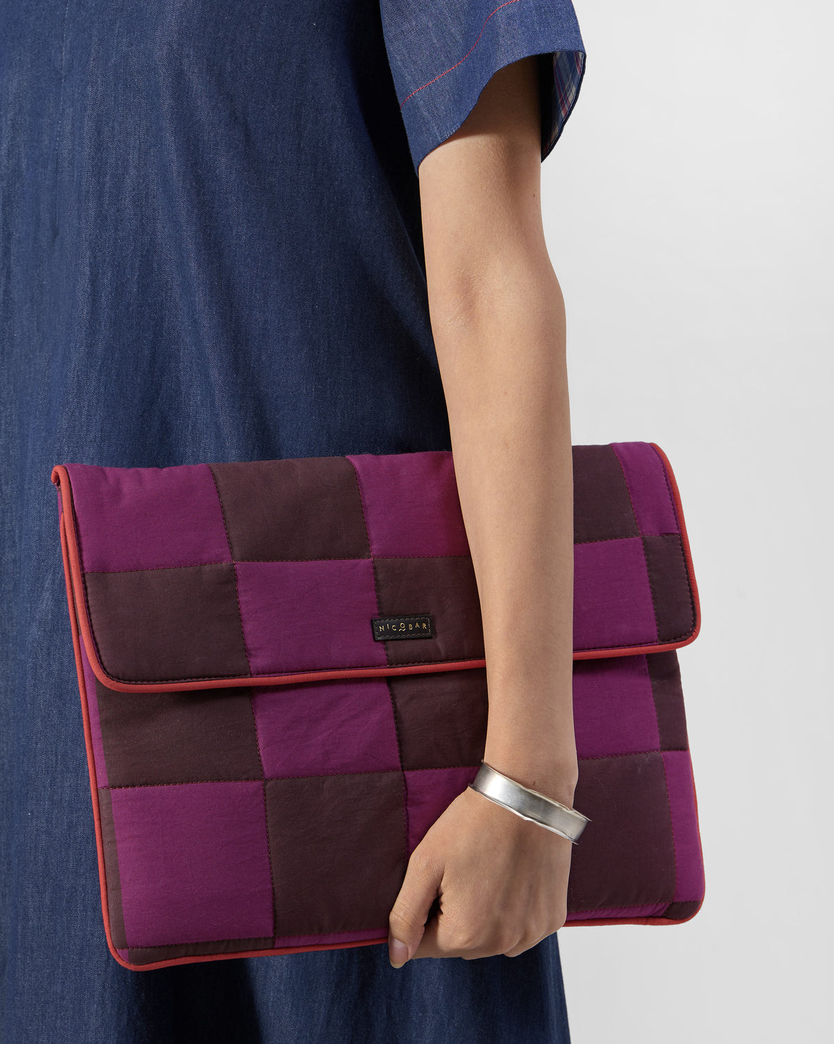 Brown and mulberry Tiled Laptop Sleeve held under an arm with red piping.
