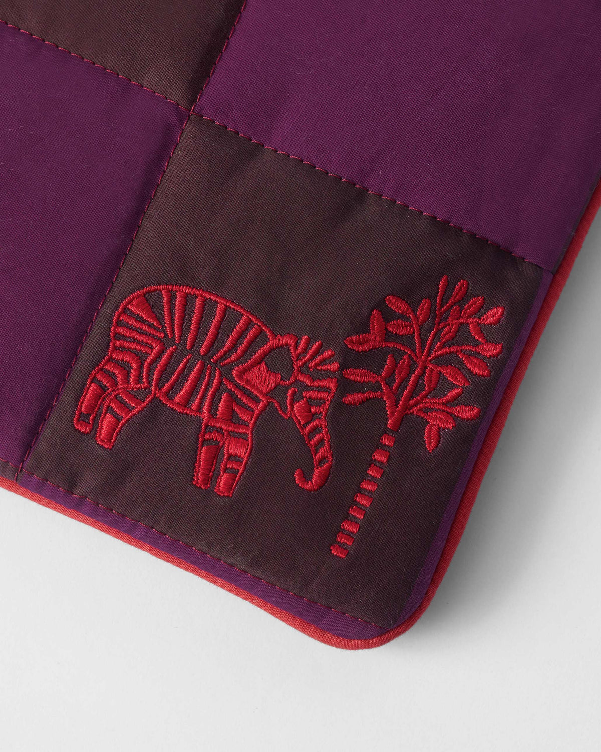 Close-up of red elephant embroidery on a brown and mulberry Tiled Laptop Sleeve.