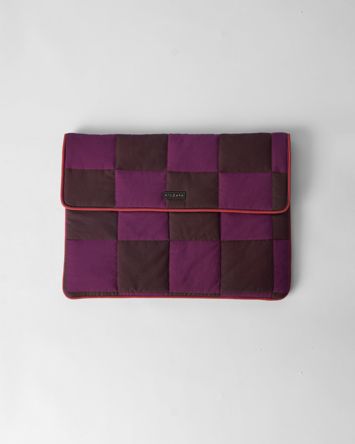 Closed brown and mulberry Tiled Laptop Sleeve with red piping and a Nicobar label.