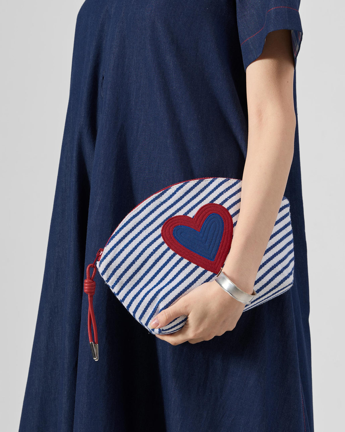 Blue and white Kira Pouch with a red heart held against the hip.