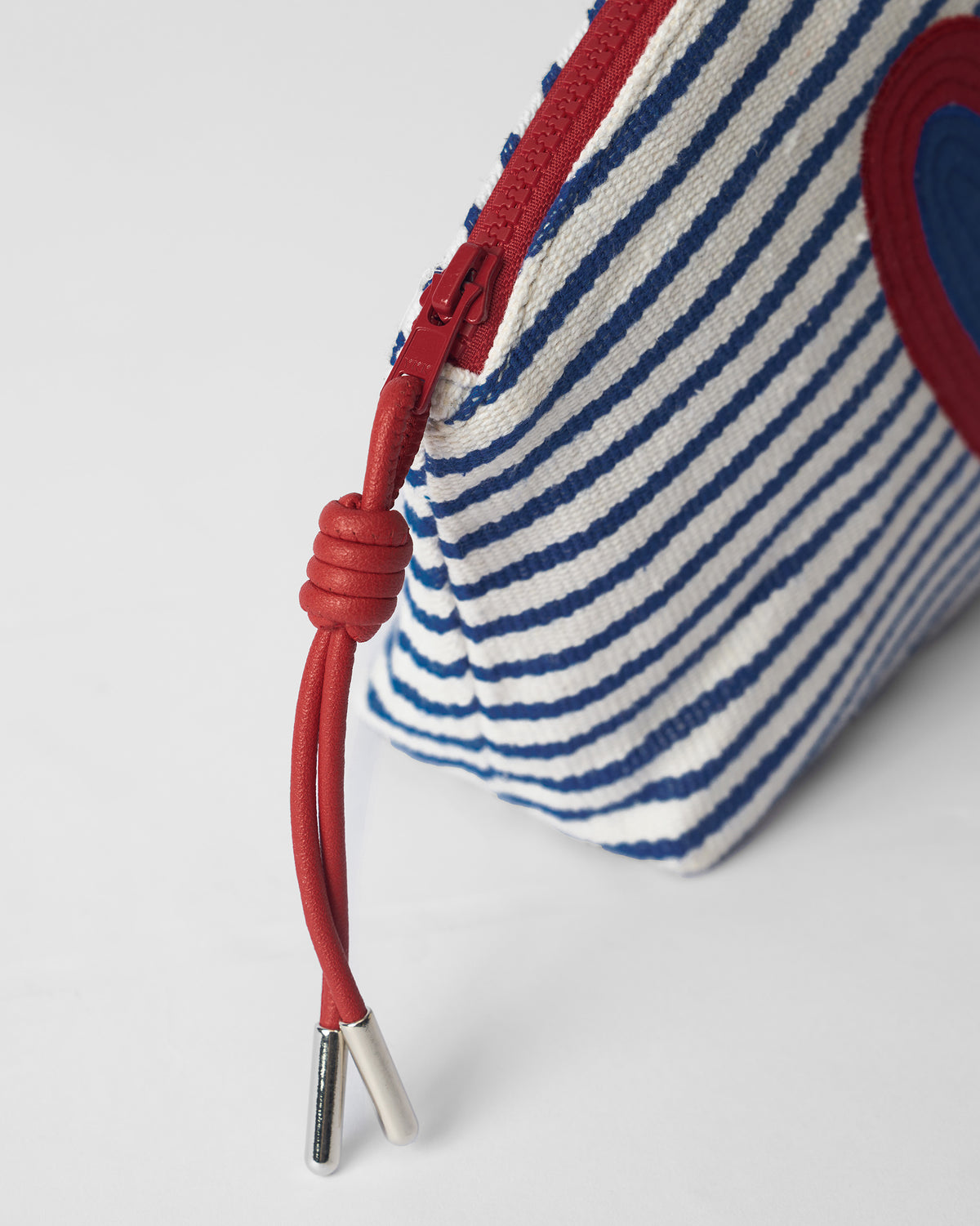 Close-up of the red zipper cord on a blue and white Kira Pouch.