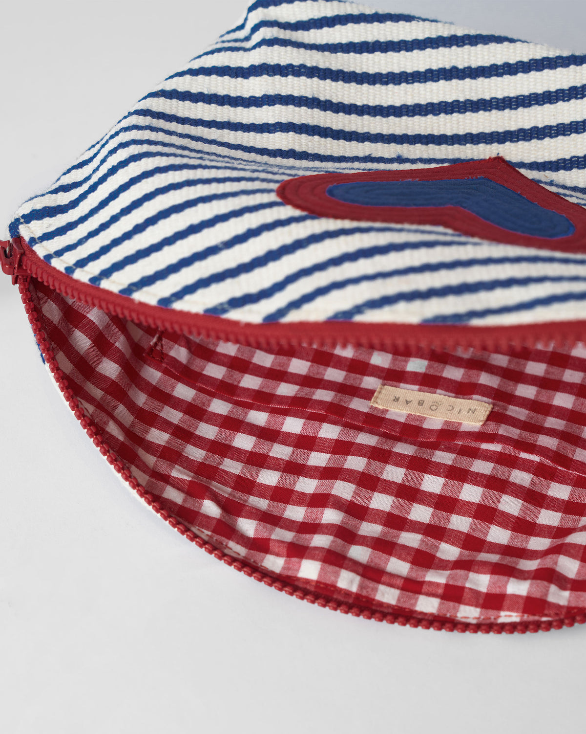 Open blue and white Kira Pouch with a red gingham lining.