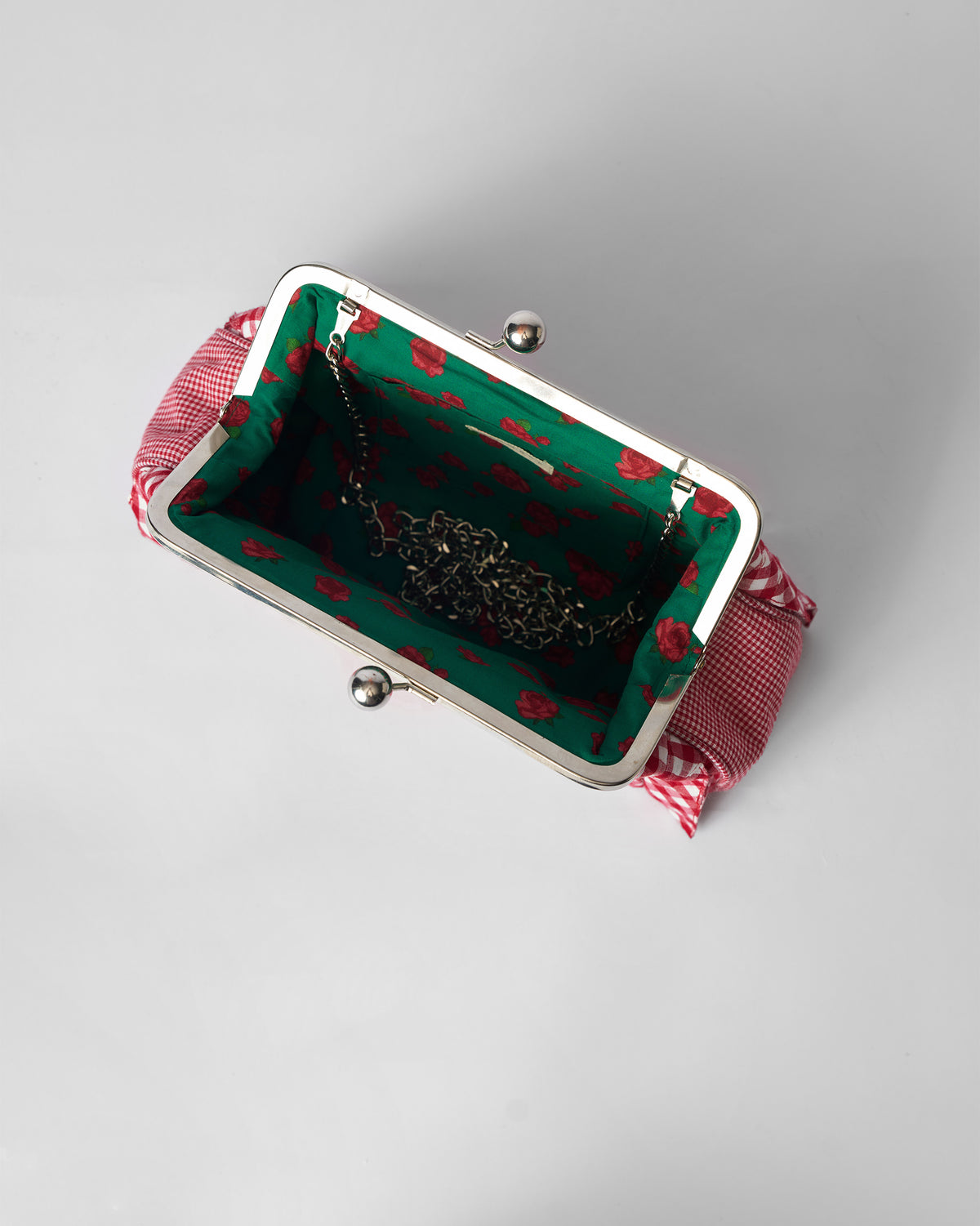 Open Pleated Muse Clutch with a green floral lining and silver chain inside.