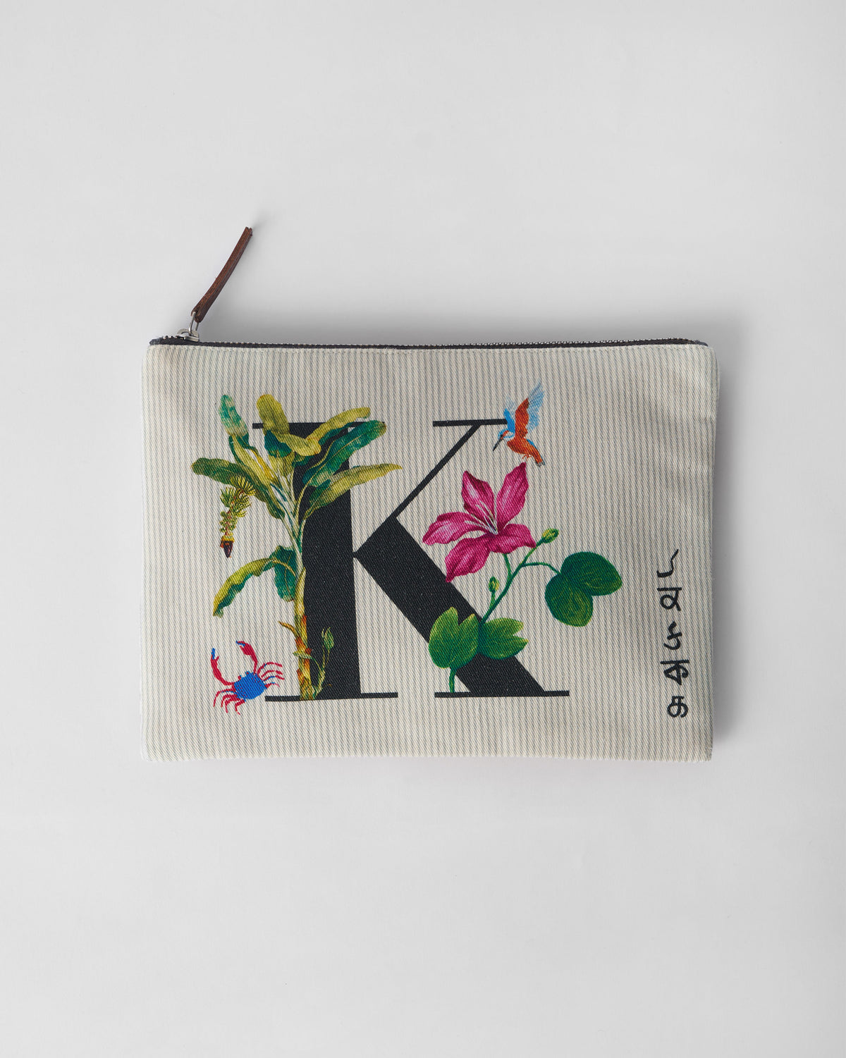 Ivory Kamal Pouch with a black K print, pink flower, and green leaves.