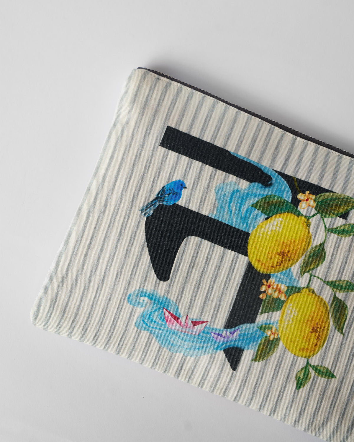 Close-up of lemon, bird, and paper boat print on an ivory Nilambari Pouch.