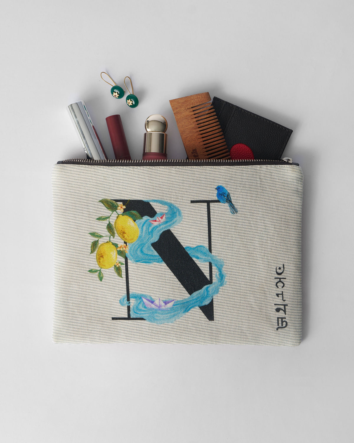 Open ivory Nilambari Pouch packed with a comb, lipstick, and small essentials.