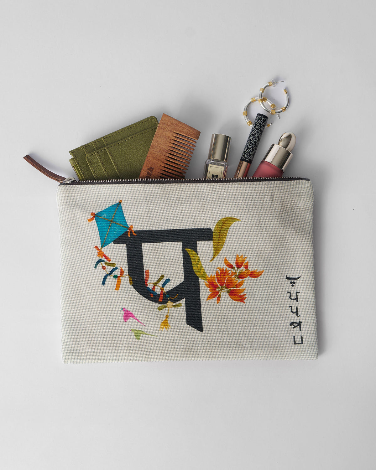 Open ivory Palash Pouch packed with a comb, wallet, and small essentials.