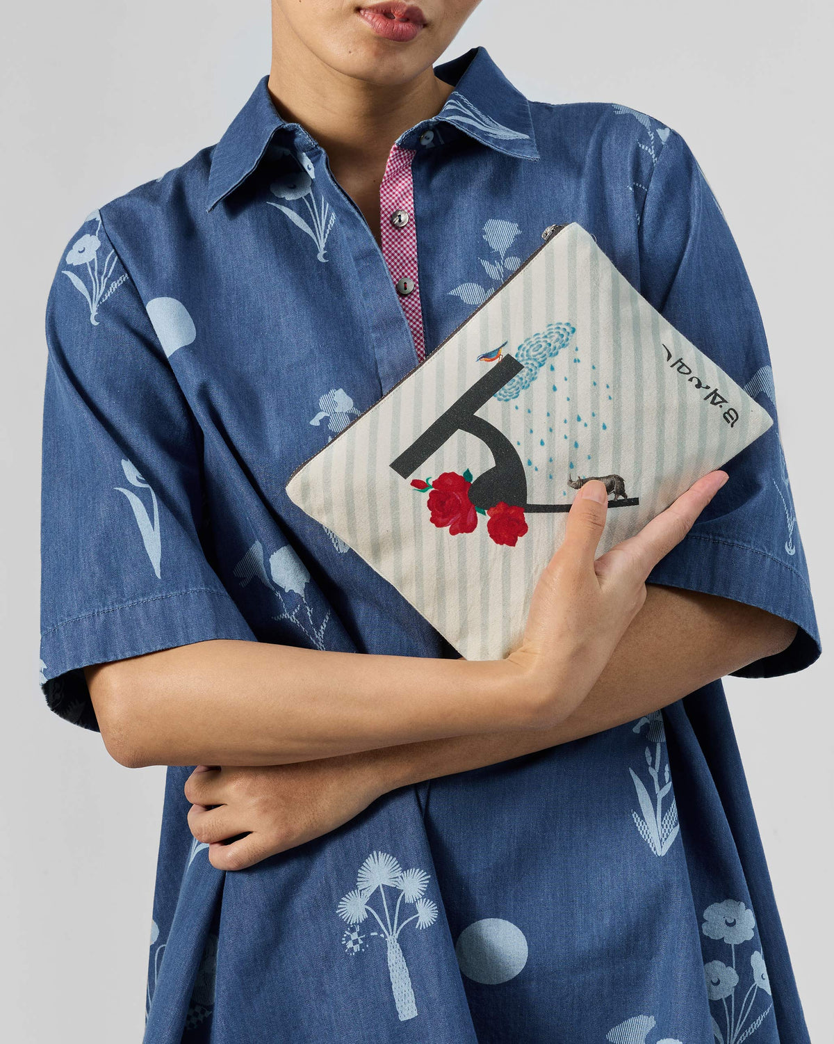 Ivory Rimjhim Pouch with a black letter print, red roses, and a rain cloud.