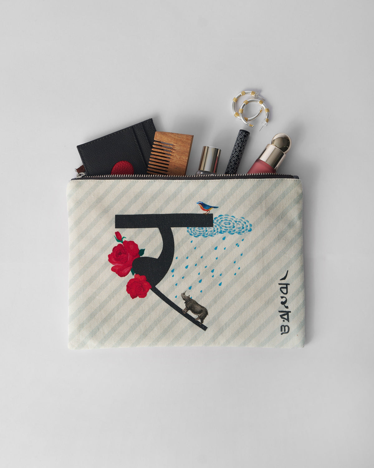 Open ivory Rimjhim Pouch packed with a comb, wallet, and small essentials.