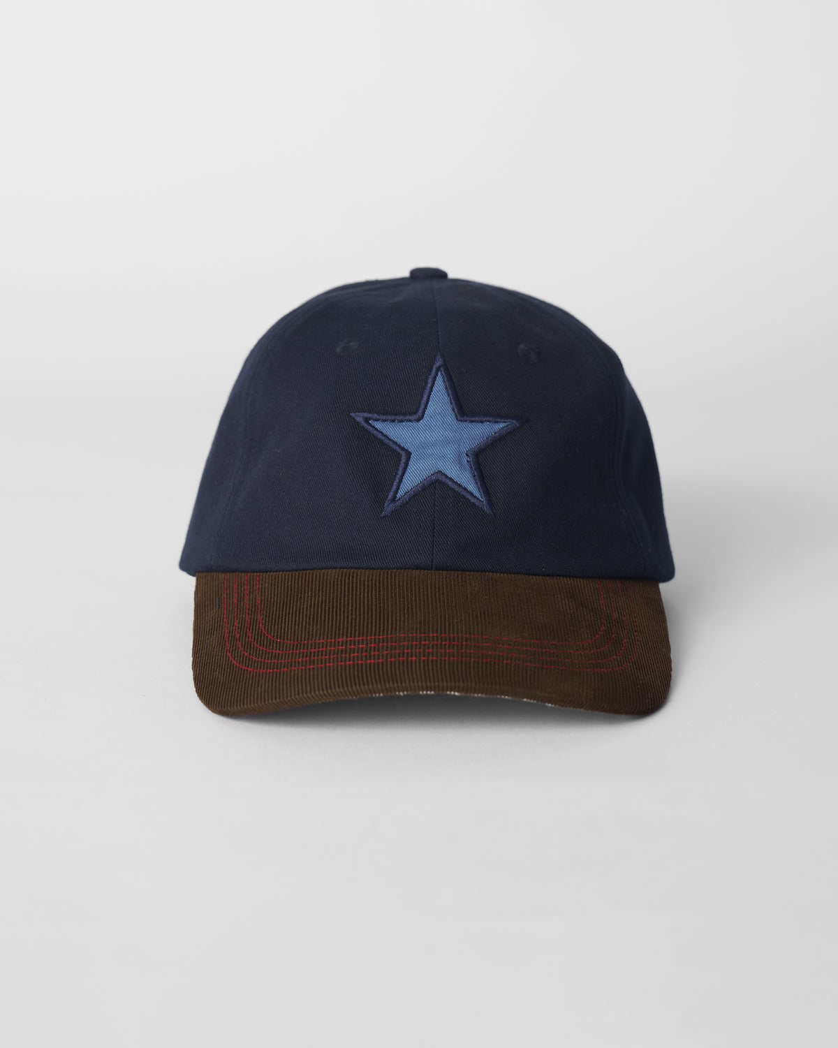 Front of a navy Starry Cap with a blue star patch and brown brim.