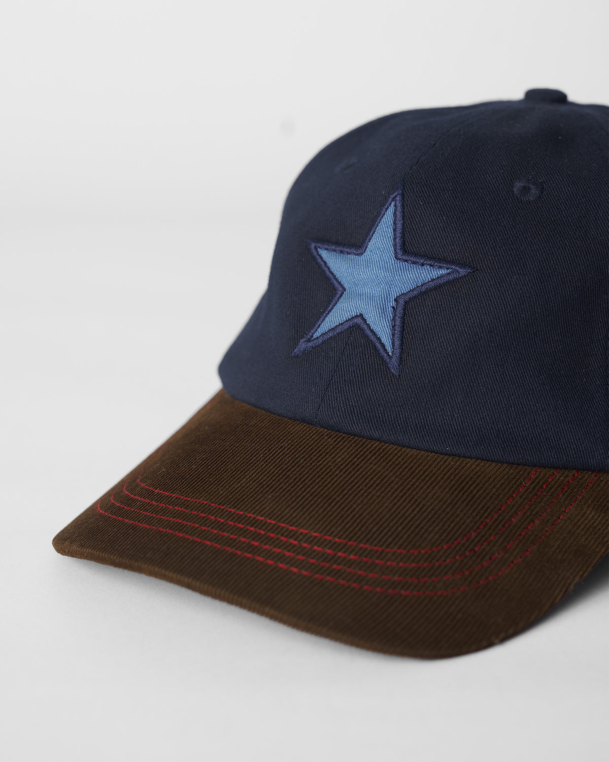 Close-up of the blue star embroidery and red stitching on the brown brim.